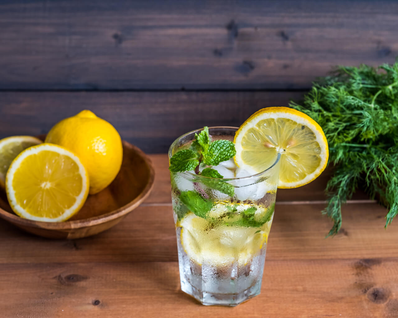 Bowl of lemons, glass of water with lemons on a table